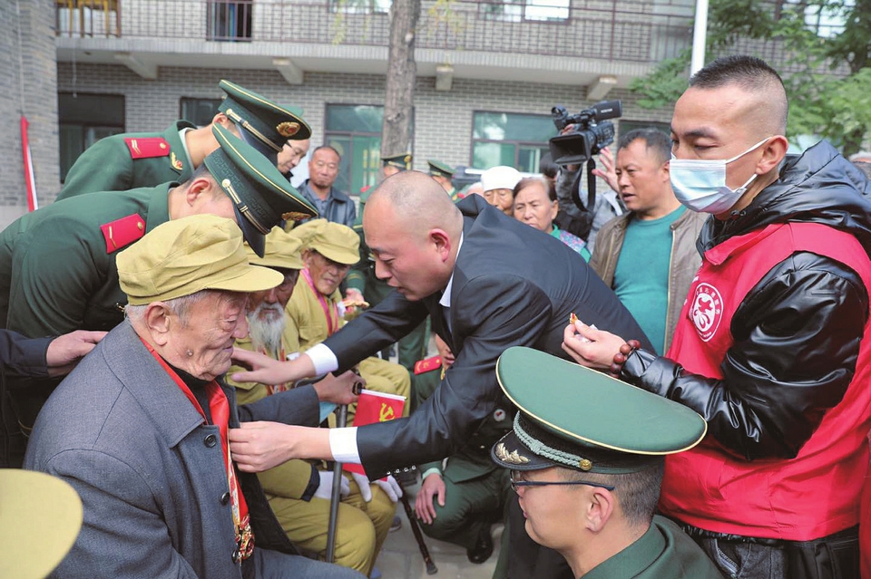 臨縣志愿者協會黨支部攜手多個黨支部開展“我幫抗美援朝老兵圓個夢”大型主題黨日活動為老黨員佩戴黨員徽章。圖片由臨縣志愿者協會提供