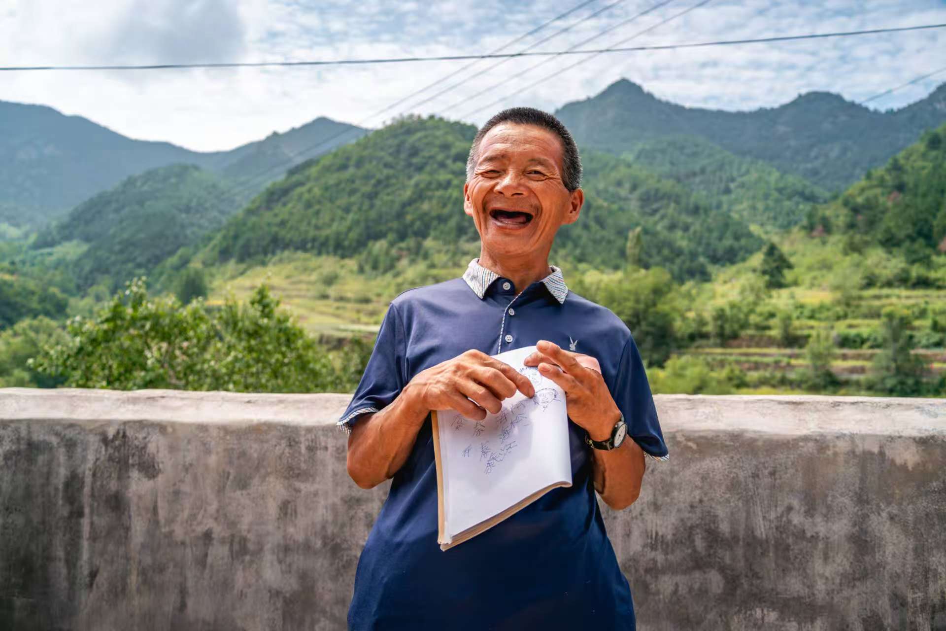 桑建國教秦海松寫名字，秦海松高興地展示。